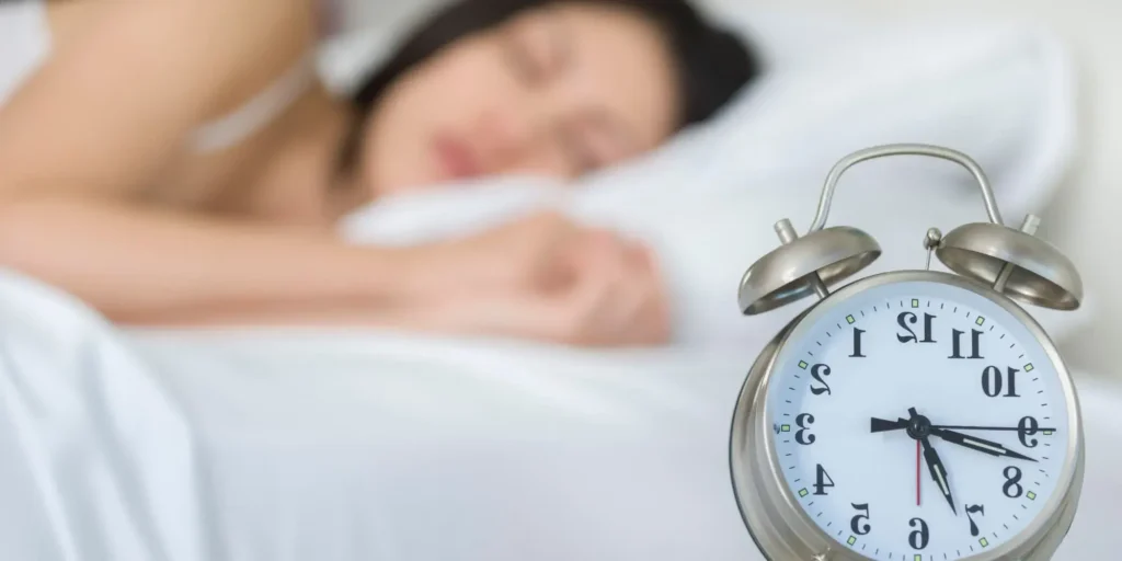 Mujer durmiendo con reloj despertador