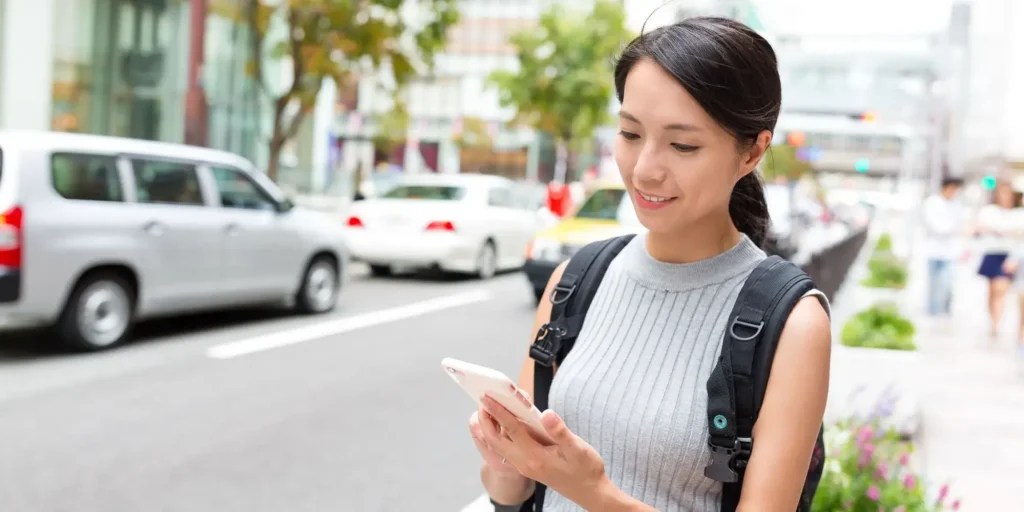 Mujer viendo celular en la calle