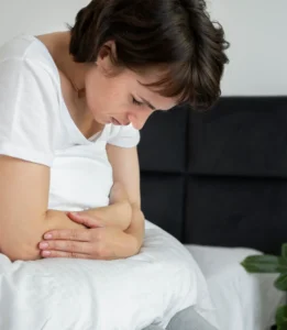 Mujer sintiendo malestar en su cama, buscando cómo aliviar el síndrome premenstrual con autocuidado