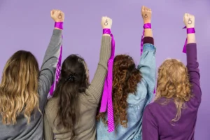 mujeres con brazo levantado sosteniendo listones en señal de protesta conmemorando el 2 de octubre Día Internacional de la No Violencia