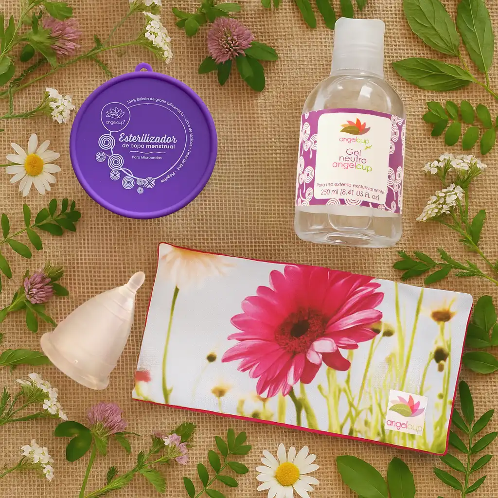 Kit completo de productos Angelcup para una menstruación sostenible: copa, vaso esterilizador, gel neutro y cojín de semillas sobre un fondo orgánico.