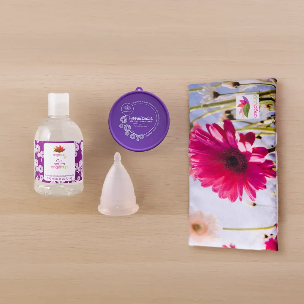Kit de cuidado esencial Angelcup: Vaso esterilizador morado, copa menstrual rosa y Gel Neutro sobre una base de madera.