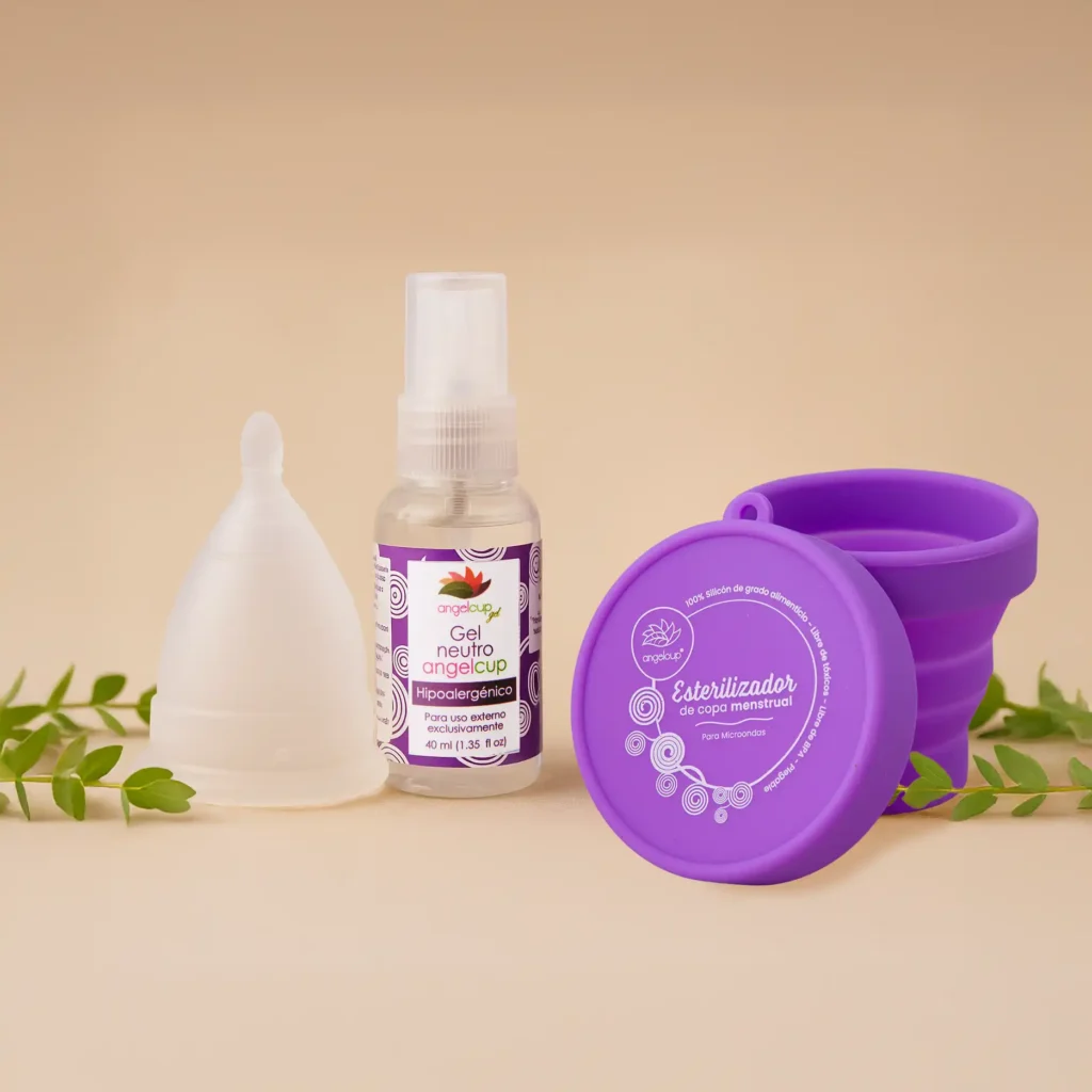 Kit de cuidado menstrual Angelcup sobre fondo beige, con copa menstrual de silicón grado médico, esterilizador morado y gel neutro limpiador. Representa una rutina íntima segura, ecológica y consciente.